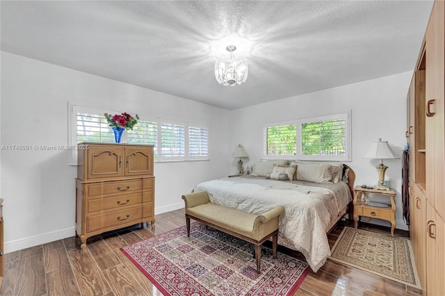 bedroom with a chandelier, wood finished floors, and baseboards