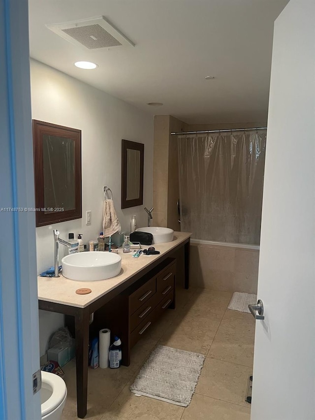 full bathroom featuring double vanity, shower / bathtub combination with curtain, visible vents, and a sink