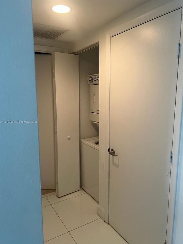 washroom featuring laundry area, light tile patterned flooring, and stacked washer and clothes dryer