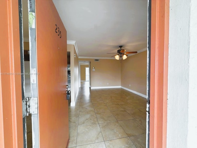 empty room featuring light tile patterned floors, visible vents, baseboards, ceiling fan, and crown molding