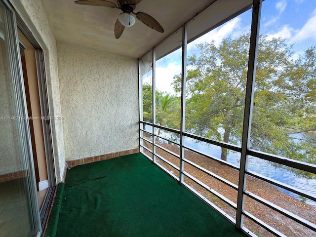 unfurnished sunroom with ceiling fan and a water view