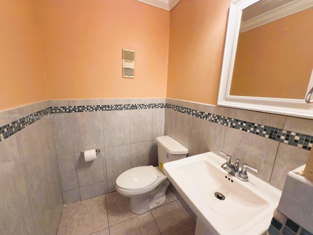 bathroom with crown molding, visible vents, toilet, a sink, and tile patterned flooring