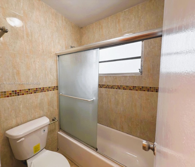 bathroom featuring shower / bath combination with glass door, tile walls, and toilet