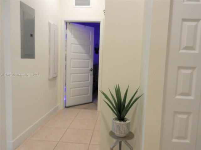 hall with light tile patterned floors, baseboards, visible vents, and electric panel