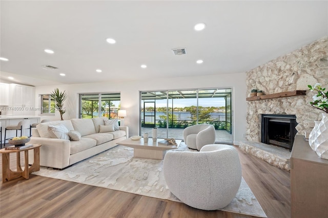 living area with light wood-style flooring, recessed lighting, visible vents, and a fireplace