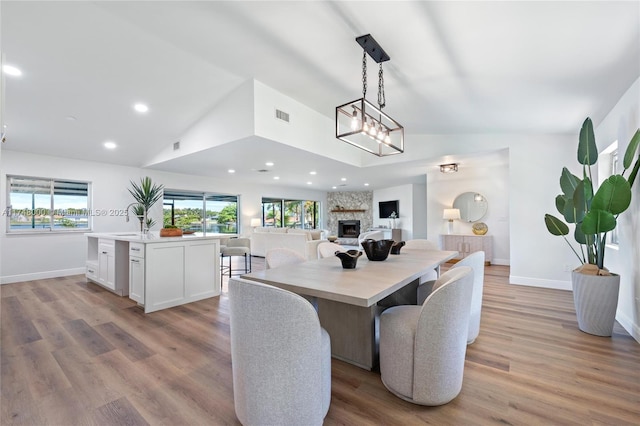 dining area with a fireplace, visible vents, light wood-style flooring, and baseboards