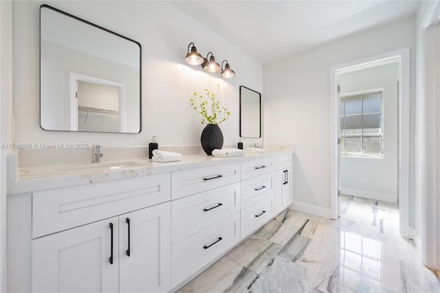 bathroom with marble finish floor, baseboards, a sink, and double vanity