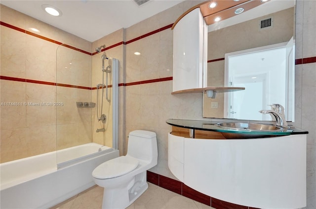 bathroom with tile patterned flooring, toilet, vanity, tile walls, and shower / bathing tub combination