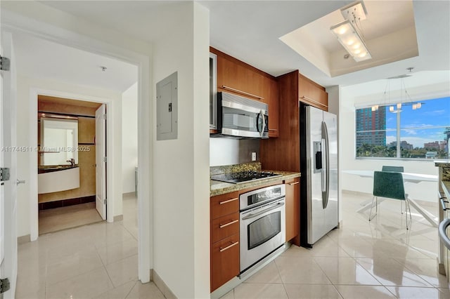 kitchen featuring light tile patterned flooring, stainless steel appliances, electric panel, a tray ceiling, and decorative light fixtures