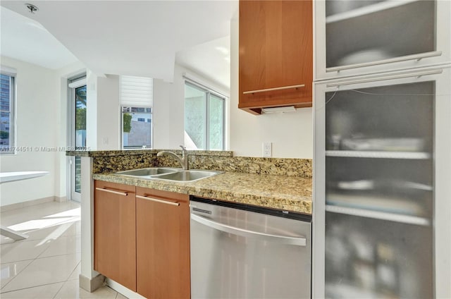 kitchen featuring light tile patterned floors, light stone countertops, a sink, brown cabinets, and dishwasher