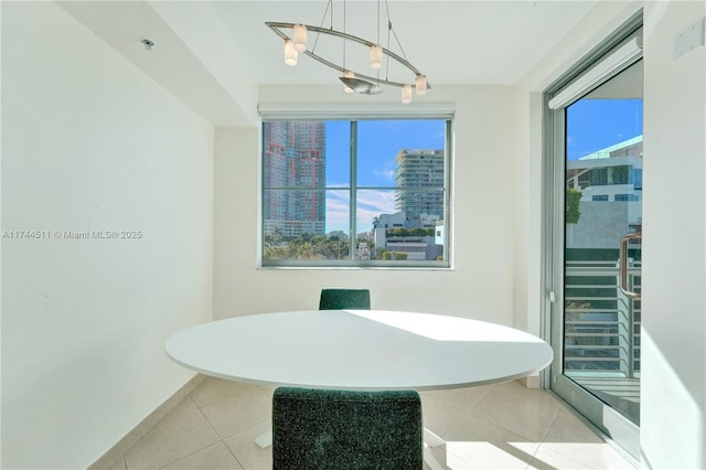 dining space with an inviting chandelier, a view of city, baseboards, and light tile patterned flooring