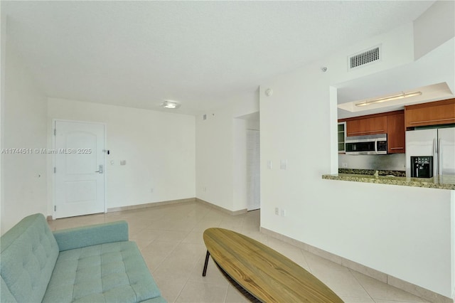 living room with light tile patterned floors, baseboards, visible vents, and a textured ceiling