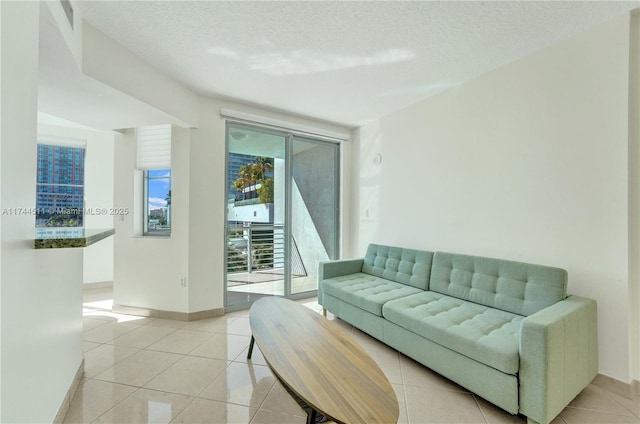 living area featuring a textured ceiling, baseboards, and light tile patterned floors