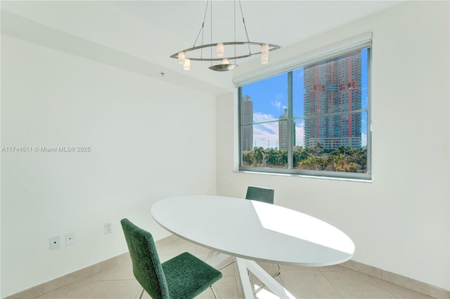 dining area featuring light tile patterned floors, a view of city, and baseboards