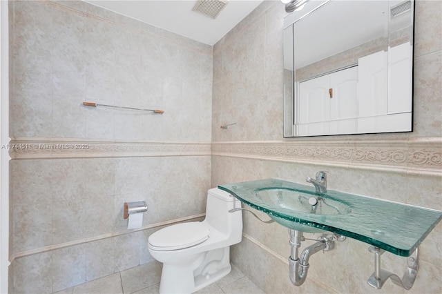 bathroom featuring visible vents, tile walls, toilet, and tile patterned floors