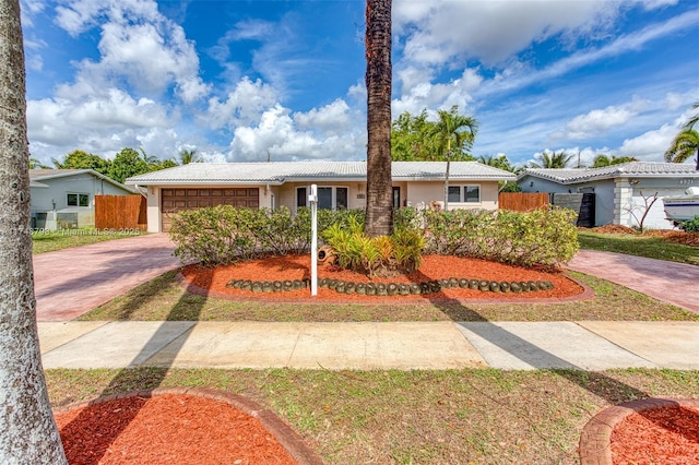 ranch-style home with a tiled roof, concrete driveway, fence, and a garage