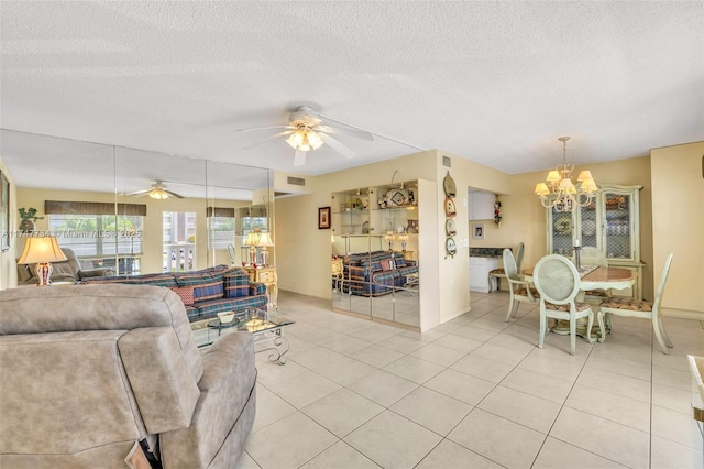 living area featuring baseboards, light tile patterned flooring, a textured ceiling, and ceiling fan with notable chandelier