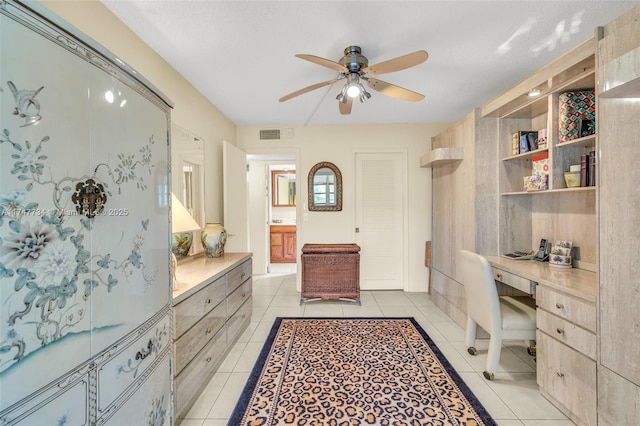 interior space with built in study area, visible vents, a ceiling fan, and light tile patterned floors