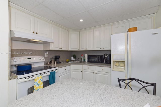 kitchen featuring white appliances, white cabinets, light countertops, under cabinet range hood, and a sink