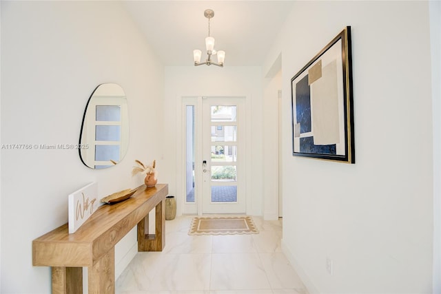 foyer featuring marble finish floor, baseboards, and an inviting chandelier