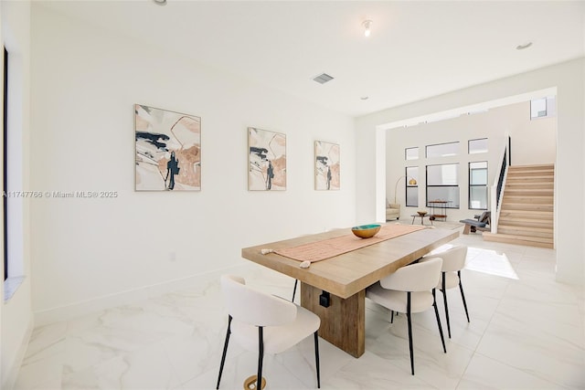 dining room featuring marble finish floor, stairway, and baseboards