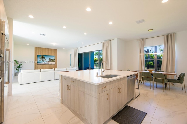 kitchen featuring light countertops, open floor plan, a sink, an island with sink, and dishwasher