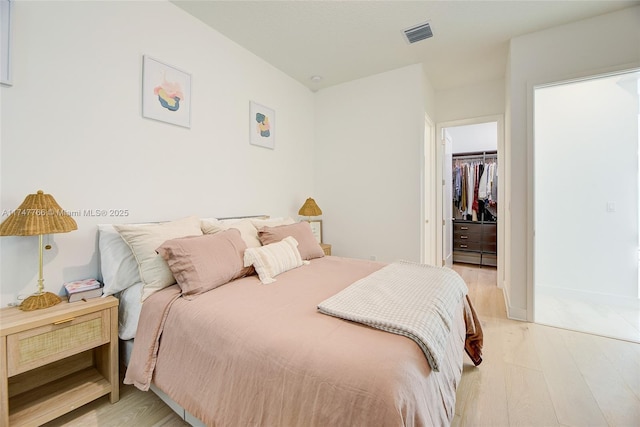 bedroom with visible vents, a spacious closet, a closet, and light wood-style flooring