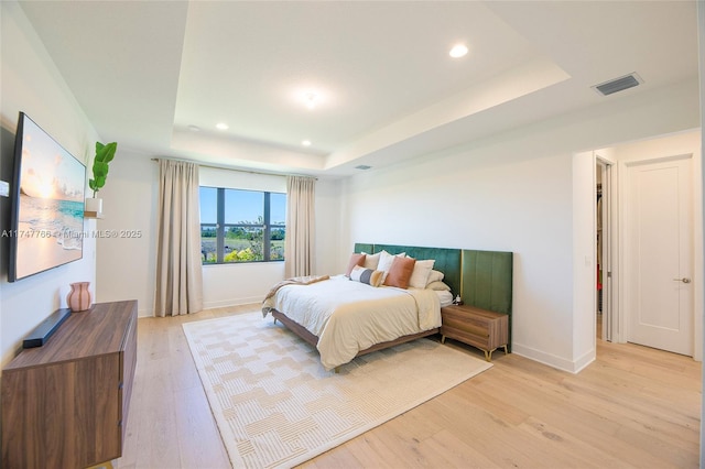 bedroom with visible vents, a tray ceiling, light wood-style flooring, and recessed lighting