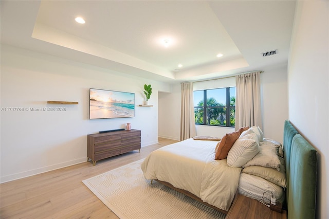 bedroom with light wood-style flooring, recessed lighting, visible vents, baseboards, and a tray ceiling