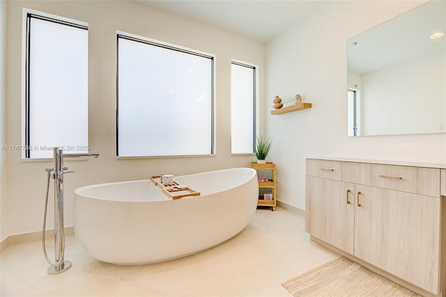 bathroom featuring tile patterned flooring, baseboards, a freestanding bath, and vanity