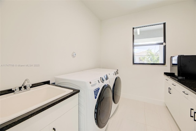 washroom with light tile patterned floors, separate washer and dryer, a sink, baseboards, and cabinet space