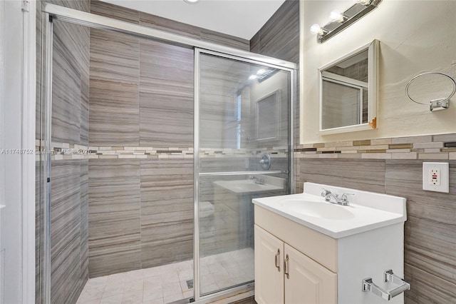 full bath featuring a stall shower, vanity, and tile walls