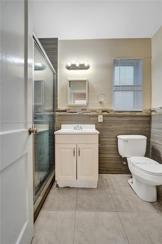 full bath with toilet, tile patterned flooring, vanity, and tile walls