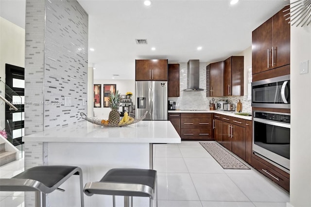 8851 SW 208th Ter, Cutler Bay, FL 33189 - kitchen with visible vents, light countertops, a kitchen bar, stainless steel appliances, and wall chimney range hood