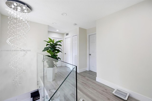 8851 SW 208th Ter, Cutler Bay, FL 33189 - hall with light wood-type flooring, visible vents, baseboards, and an inviting chandelier