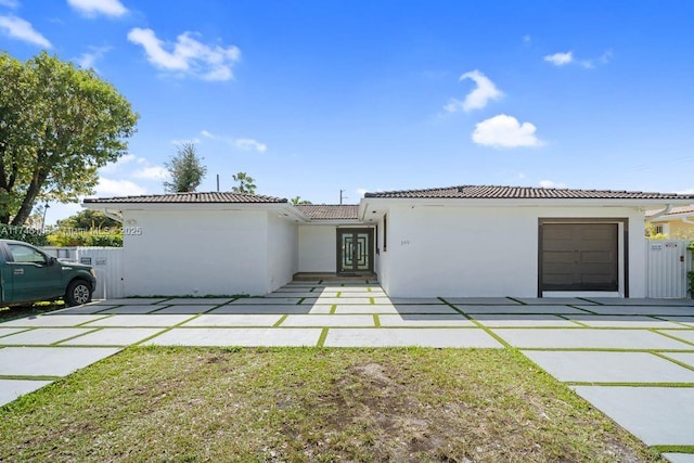 view of front of home with a front lawn, an attached garage, a tile roof, and stucco siding