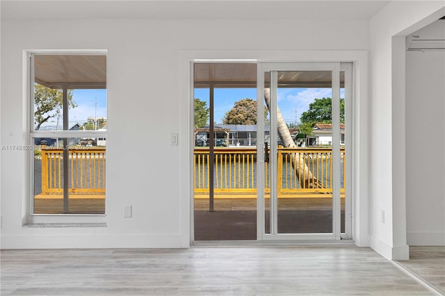 entryway featuring a healthy amount of sunlight, a water view, baseboards, and wood finished floors