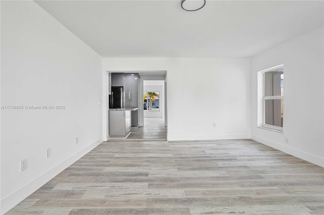 spare room featuring light wood-style flooring and baseboards