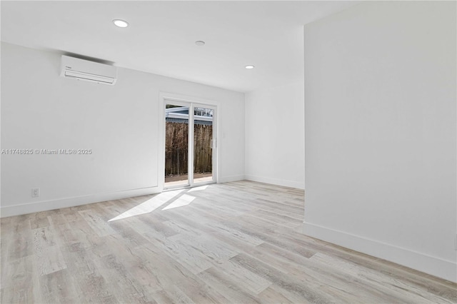 empty room with a wall mounted AC, recessed lighting, light wood-style flooring, and baseboards