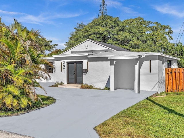 view of front of house with a front lawn, fence, and stucco siding