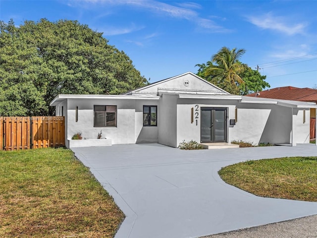 view of front of home with stucco siding, a front lawn, and fence