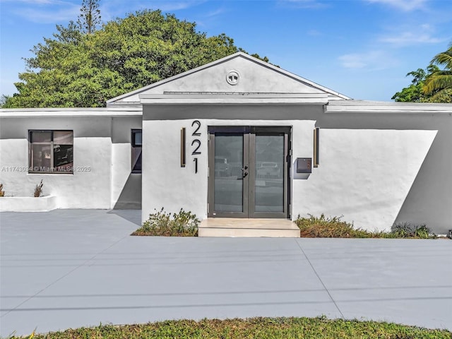 property entrance featuring stucco siding and french doors