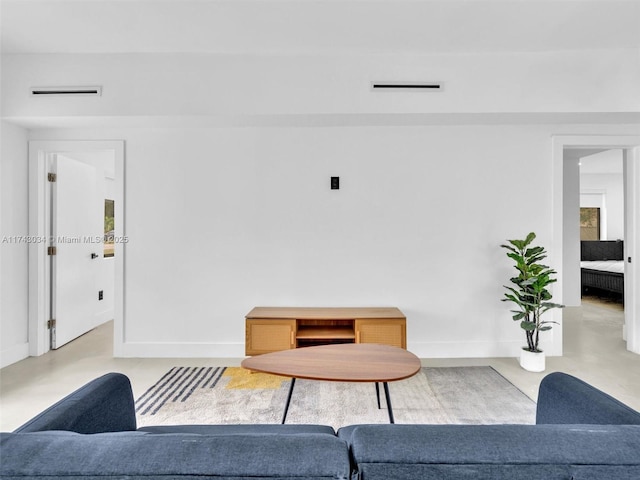 living area with visible vents, concrete flooring, and baseboards