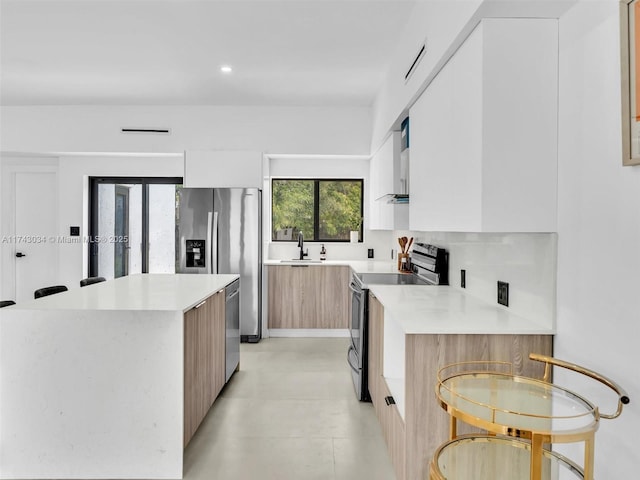 kitchen with a center island, light countertops, stainless steel appliances, modern cabinets, and a sink