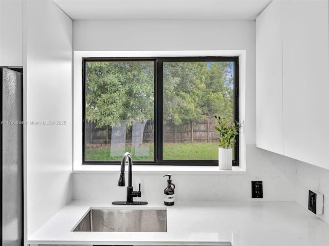 kitchen featuring refrigerator, plenty of natural light, and a sink