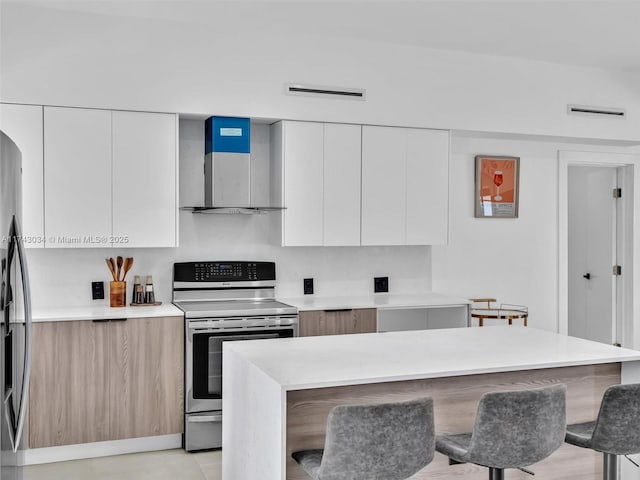 kitchen with electric range, wall chimney exhaust hood, and modern cabinets