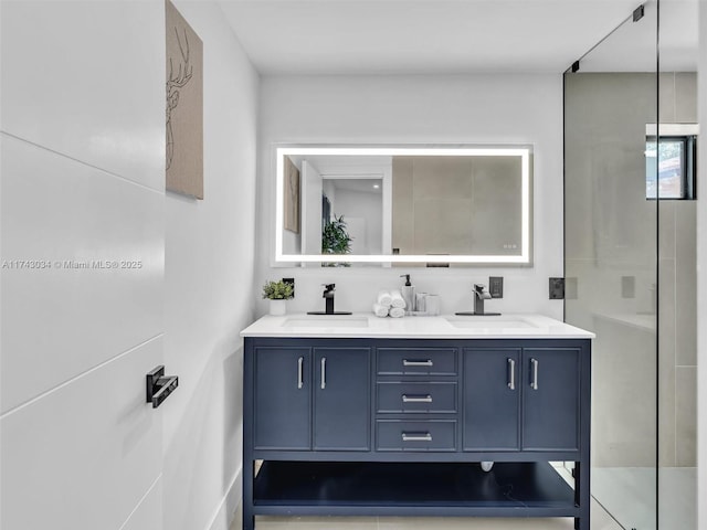 bathroom featuring double vanity, a shower with shower door, and a sink