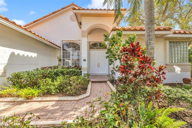 entrance to property featuring a tiled roof and stucco siding