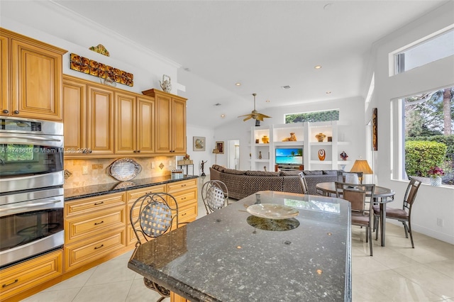 kitchen with plenty of natural light, dark stone counters, open floor plan, and stainless steel double oven