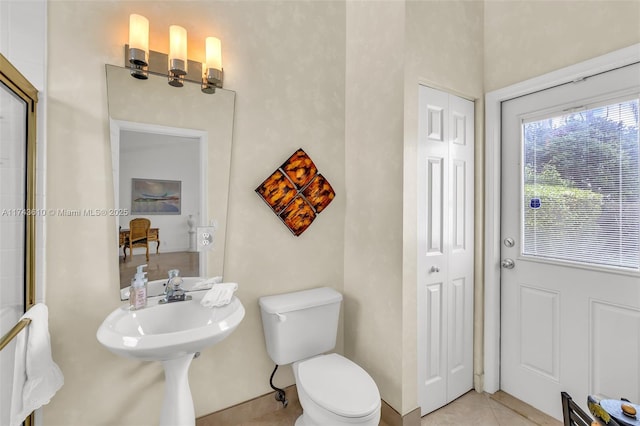 bathroom with toilet, a closet, and tile patterned floors